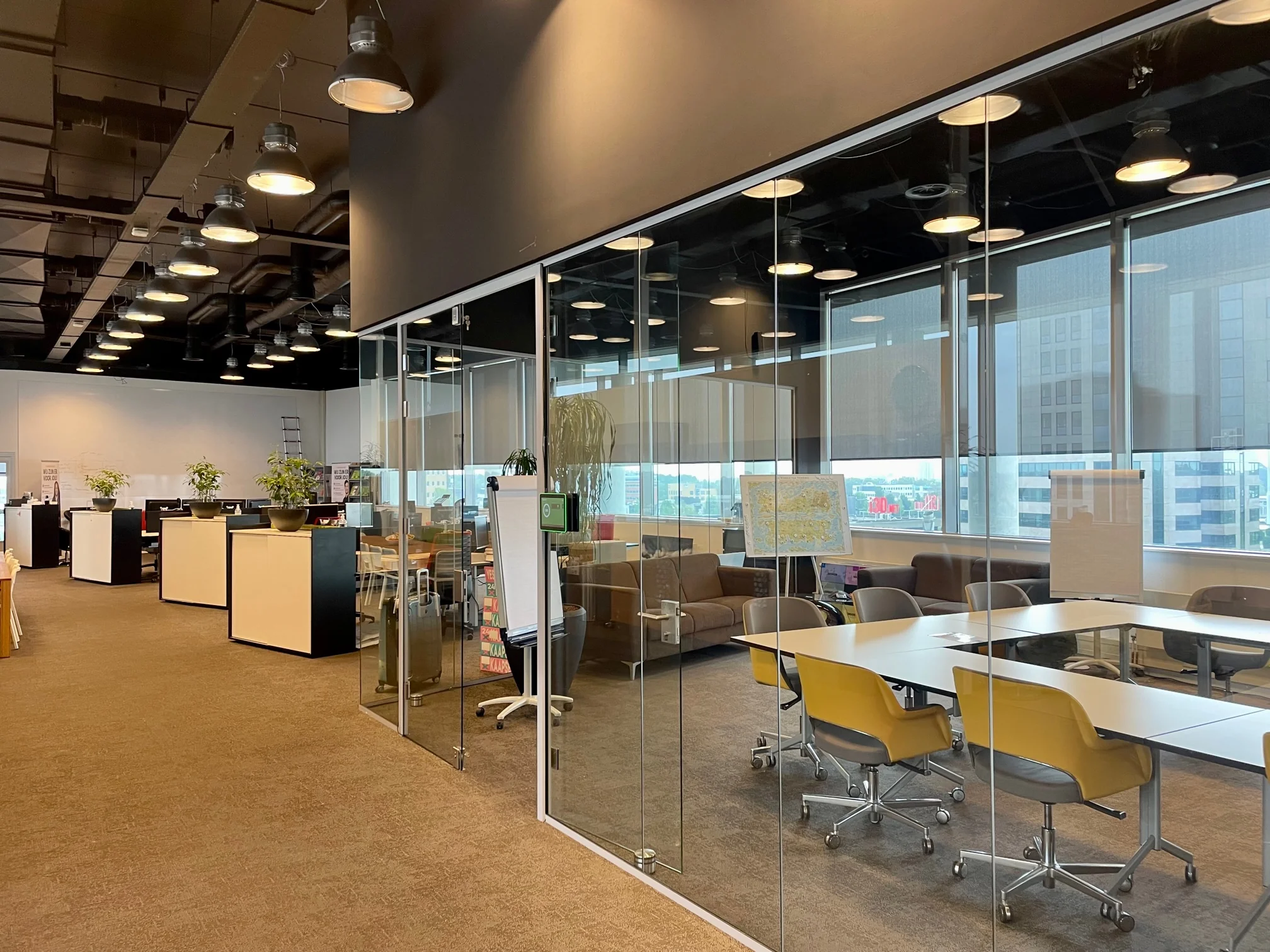 Moderne kantoorruimte in het Rivium Quadrant met glazen vergaderruimte, bureaus en zithoek.